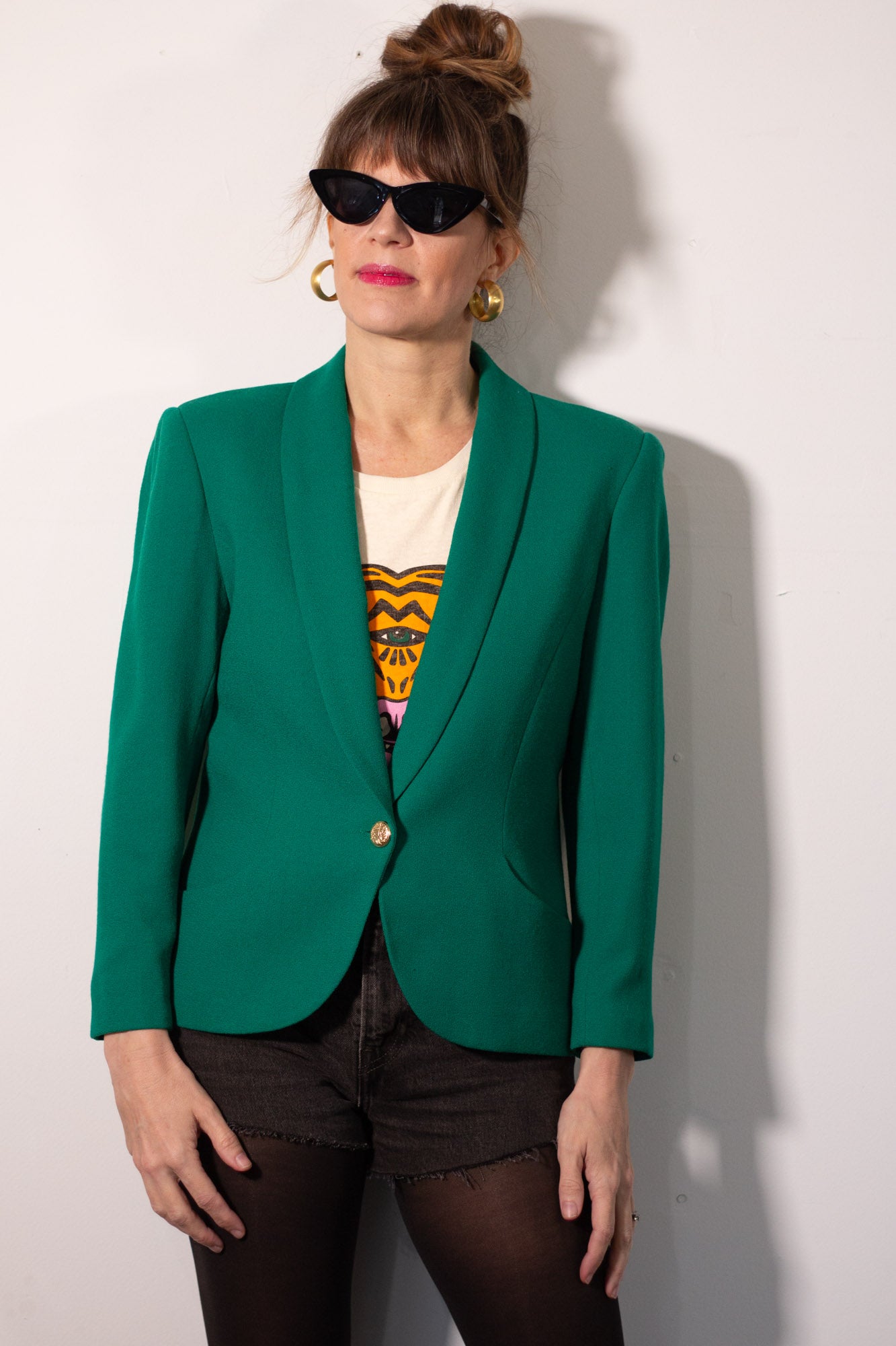 Person wearing a green blazer over a colorful top against a white background