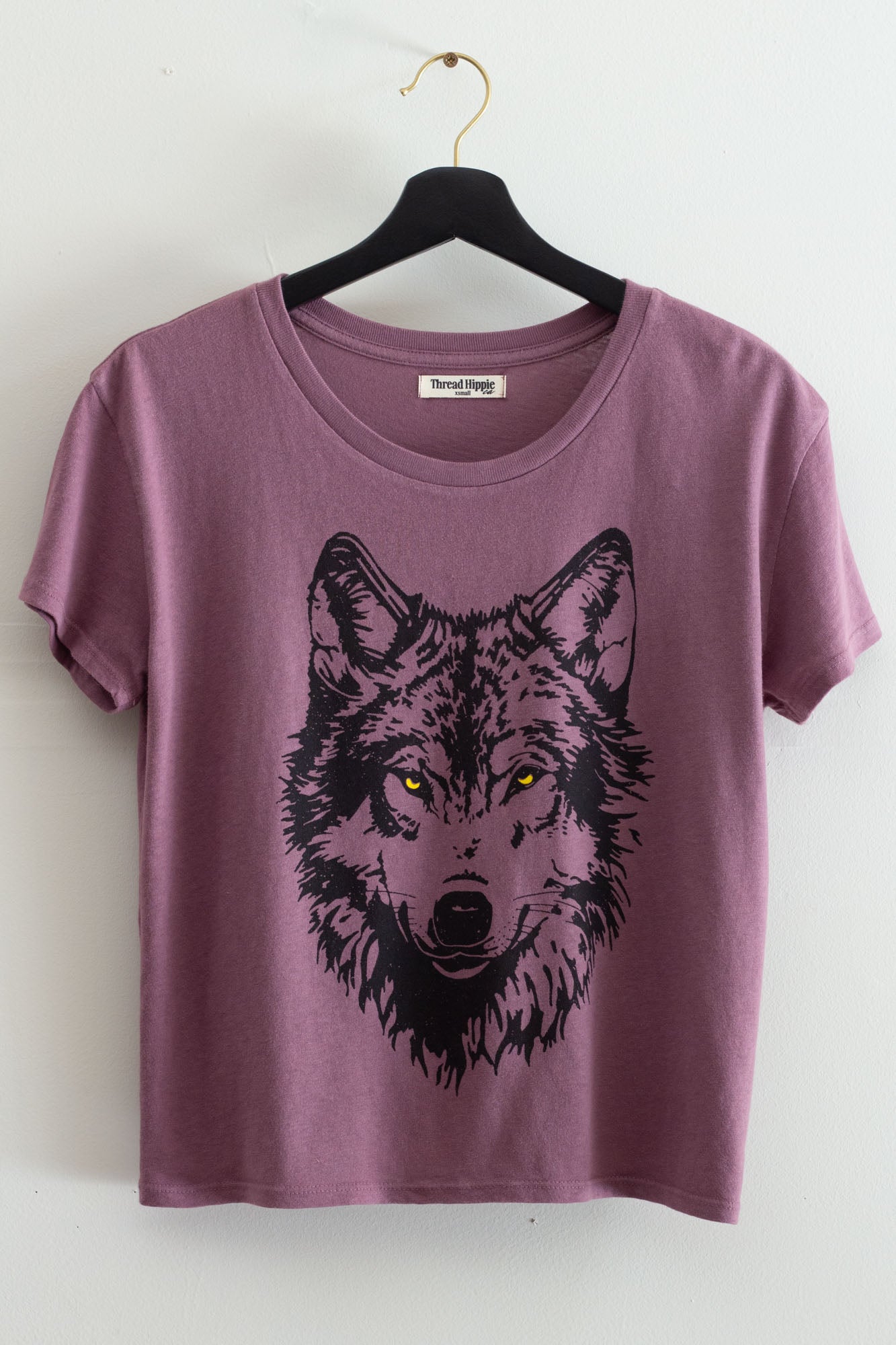Purple t-shirt with a wolf graphic on a hanger against a white background.