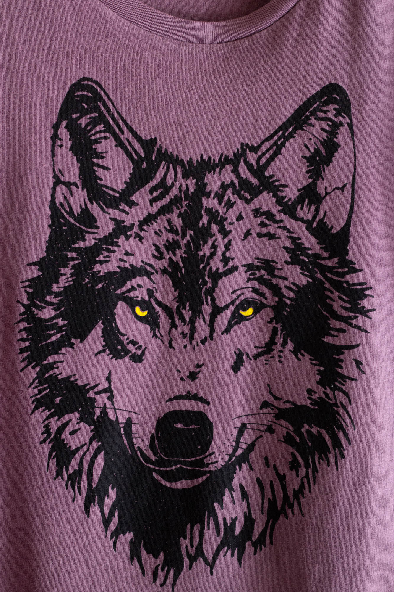 Purple t-shirt with a black wolf graphic on a plain background.