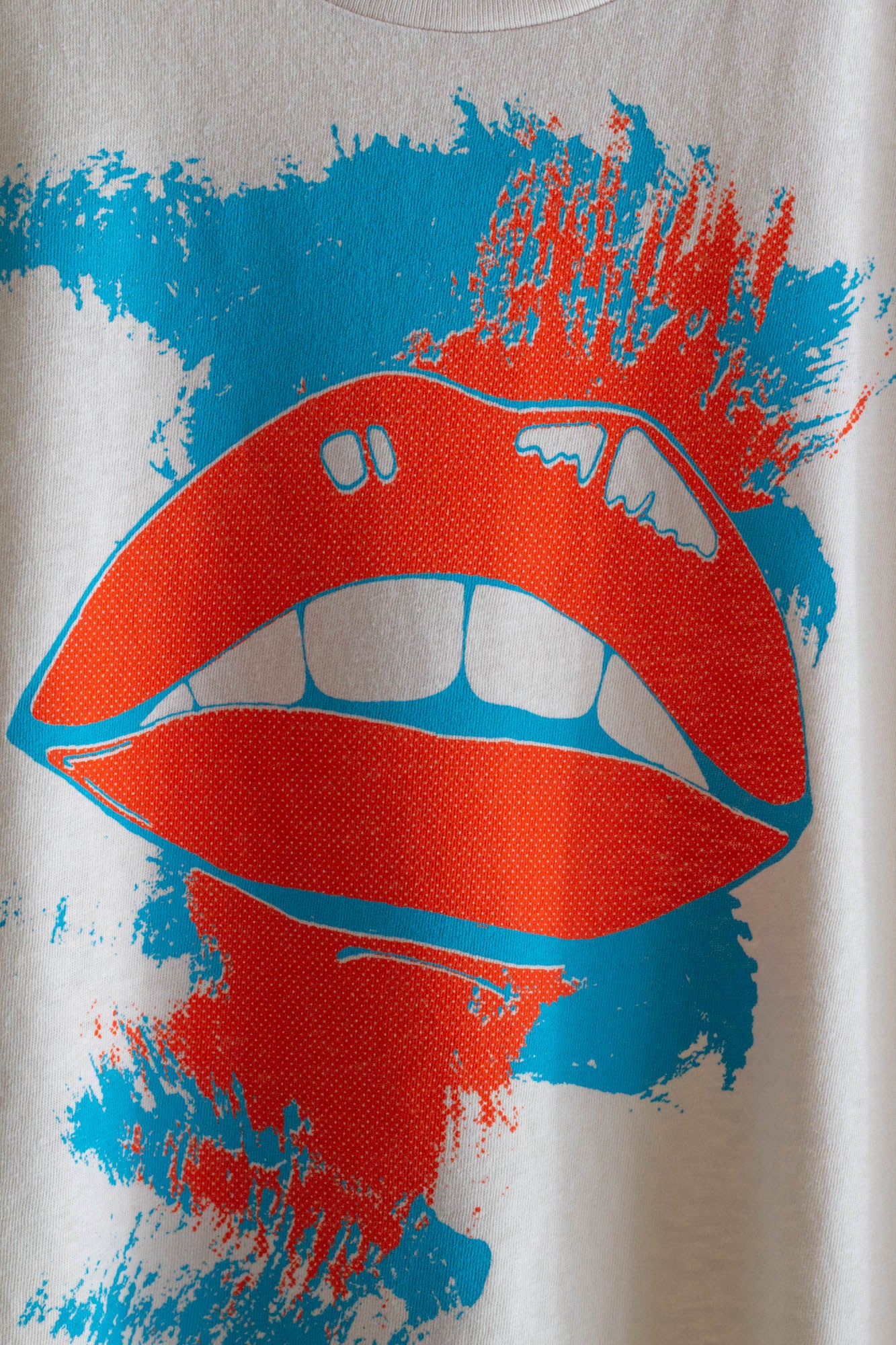 Women's T-shirt with red lips and blue paint splashes on a white background.