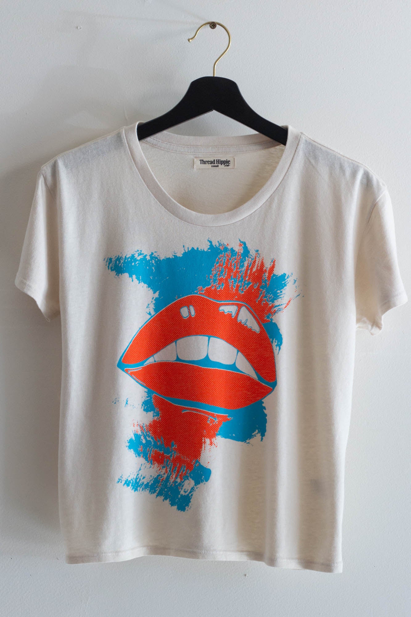 White t-shirt with red lips graphic design on a hanger against a white background.