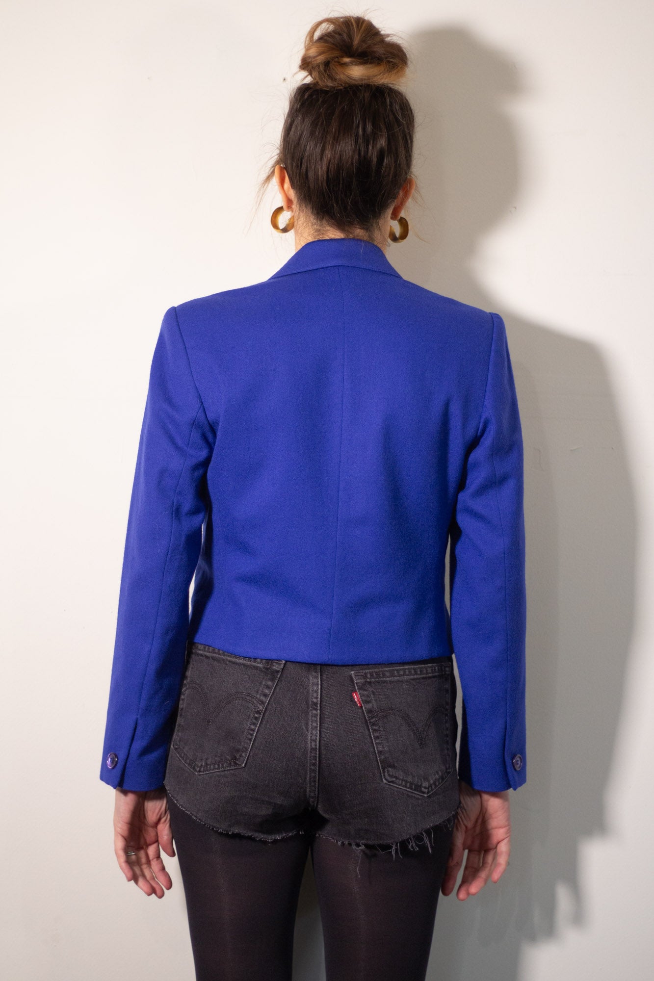 Person wearing a blue blazer from behind on a plain background