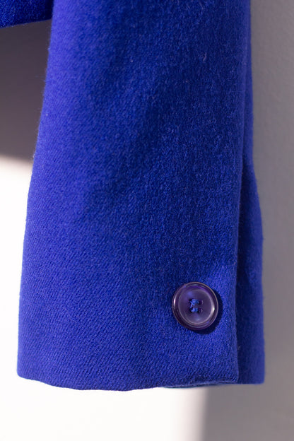 Close-up of a blue coat with a button on a gray background