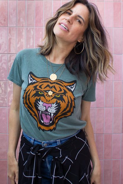 Woman wearing a t-shirt with a tiger graphic design against a pink tiled wall.