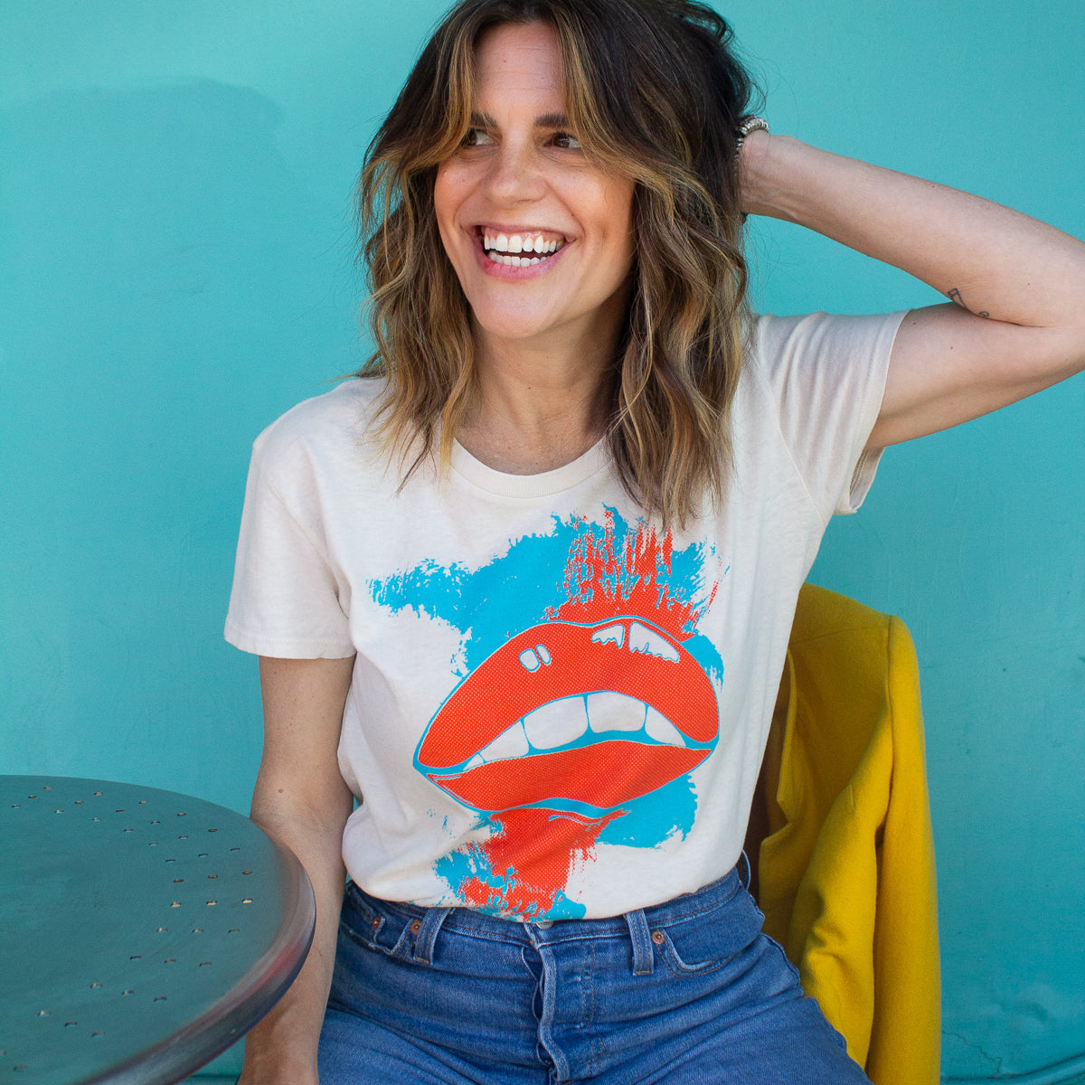 Woman wearing a Thread Hippie graphic t-shirt with red lips against a teal background.