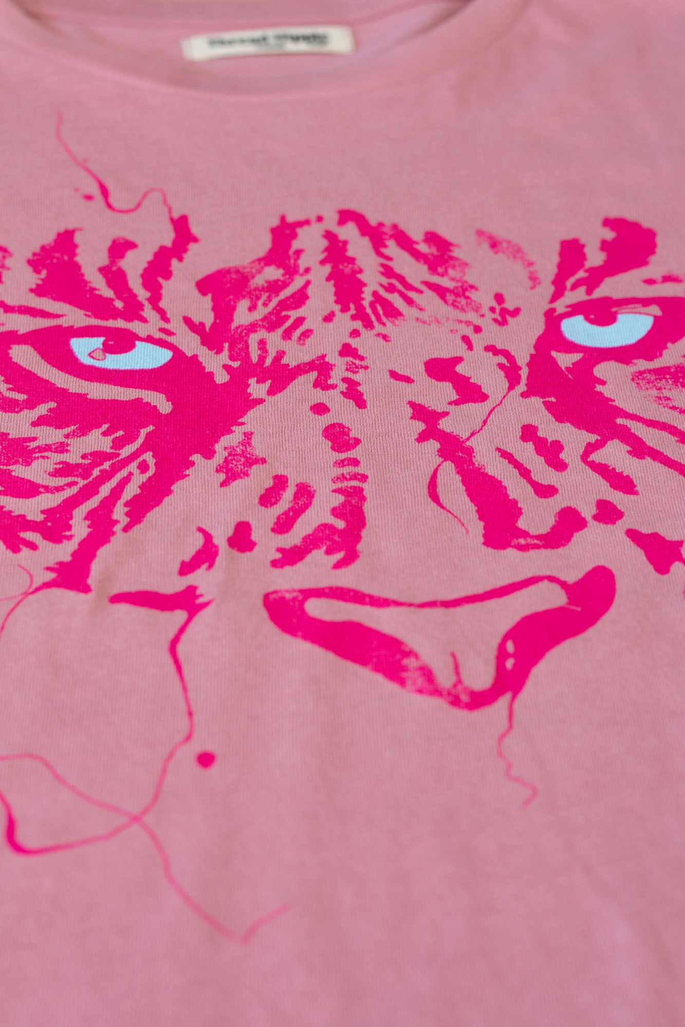 Pink t-shirt with a stylized tiger design on a pink background.