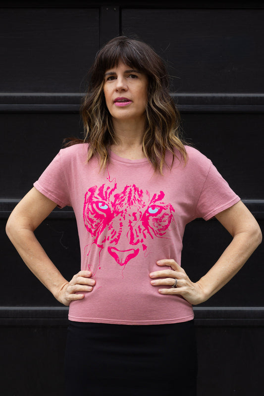 Woman wearing a pink t-shirt with a pink tiger graphic against a black background.