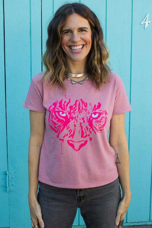 Woman wearing a pink t-shirt with a graphic design of a tiger's face against a teal background.