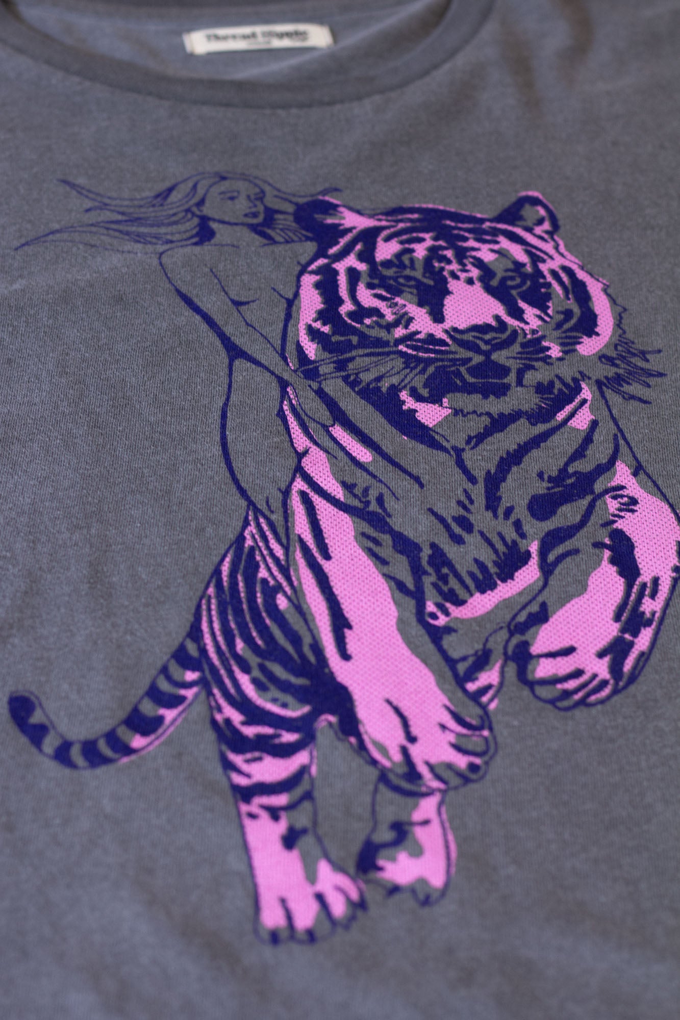 Gray t-shirt with a pink tiger design on a dark background.