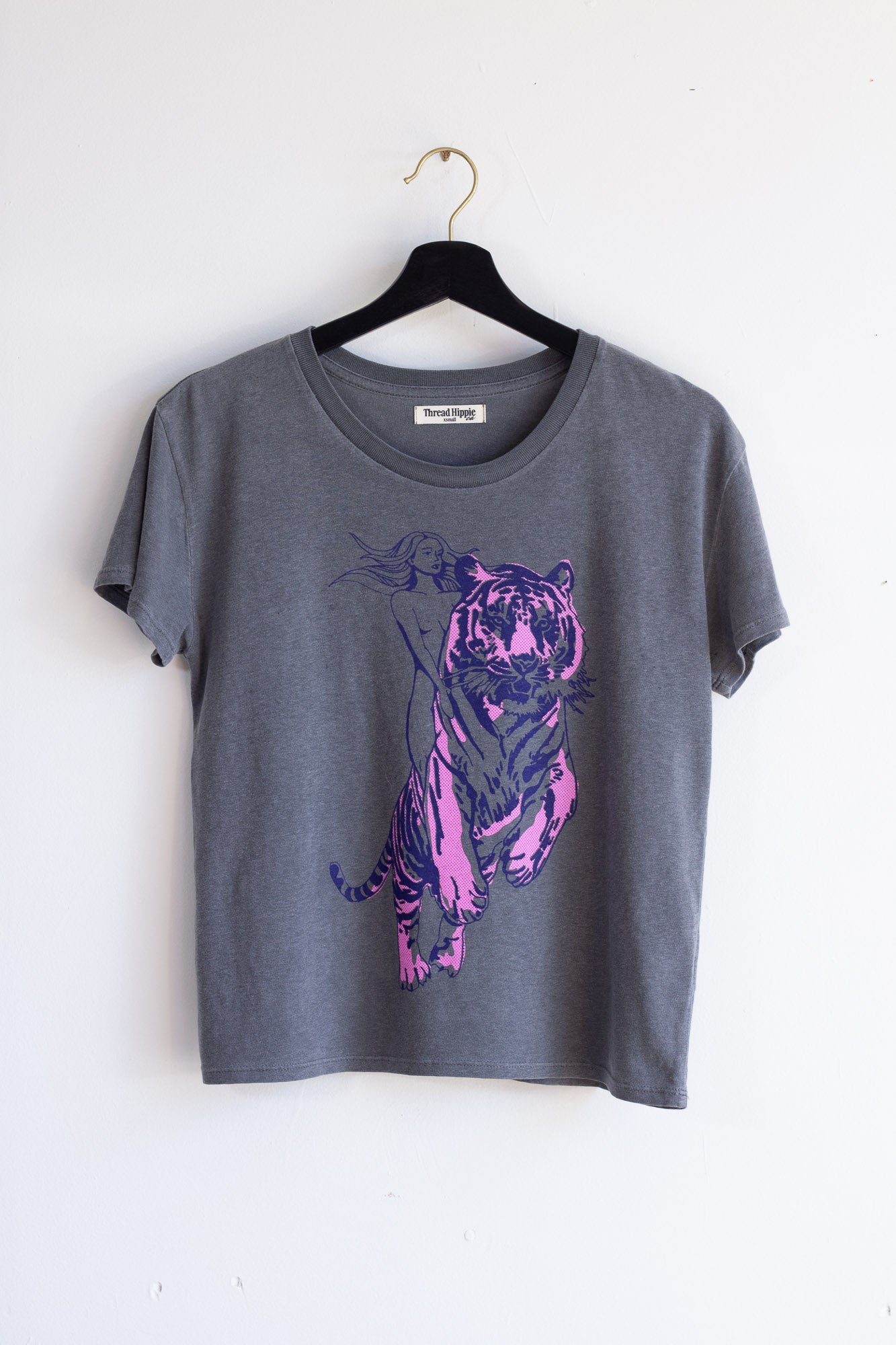 Gray t-shirt with a purple tiger design on a hanger against a white background.