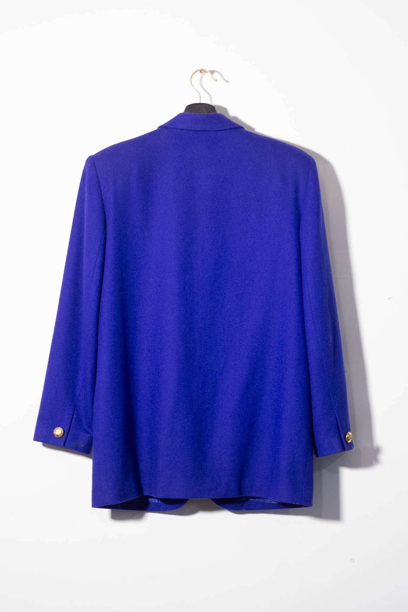 Blue blazer on a hanger against a white background