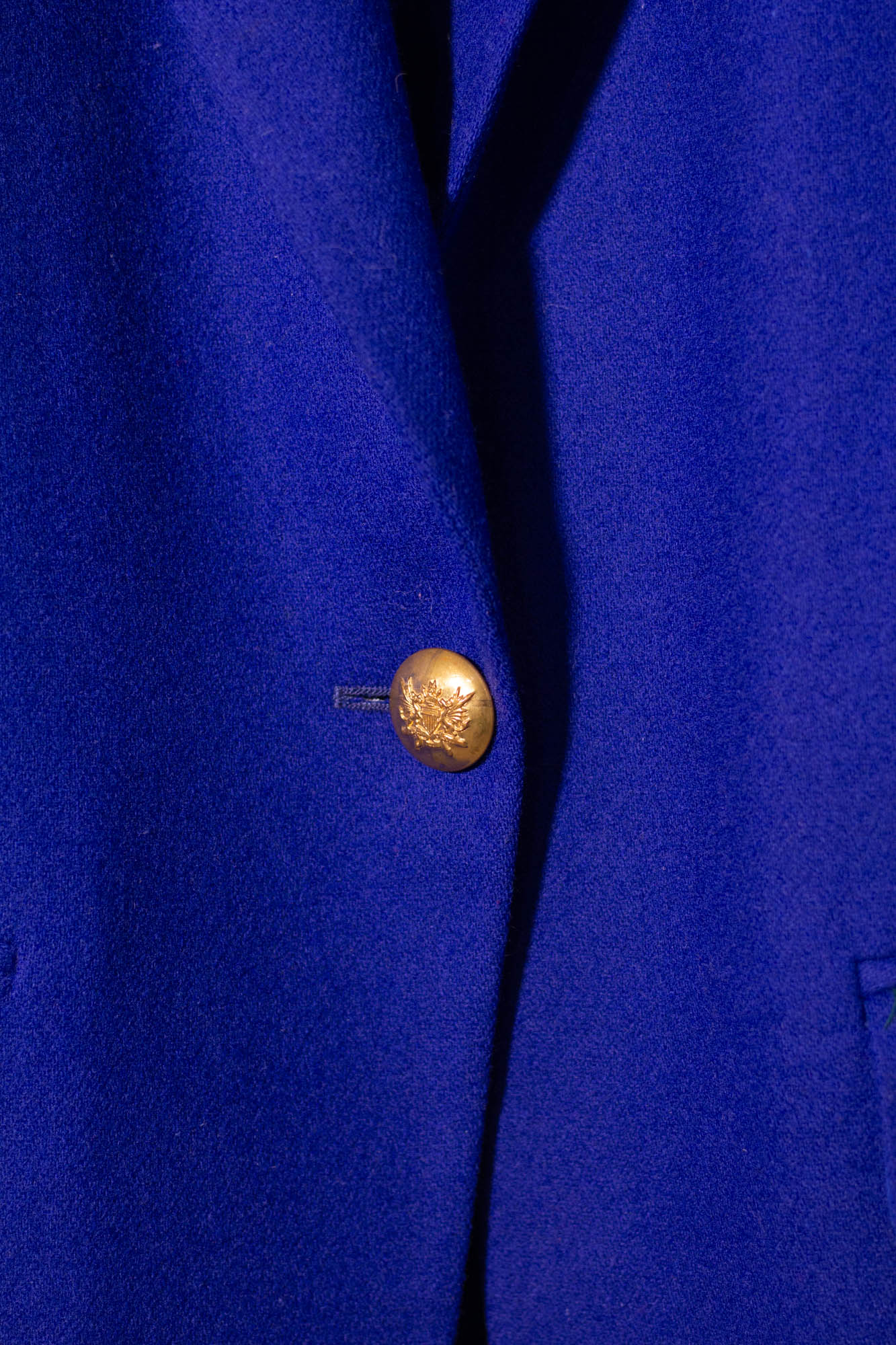 Close-up of a blue jacket with a gold button