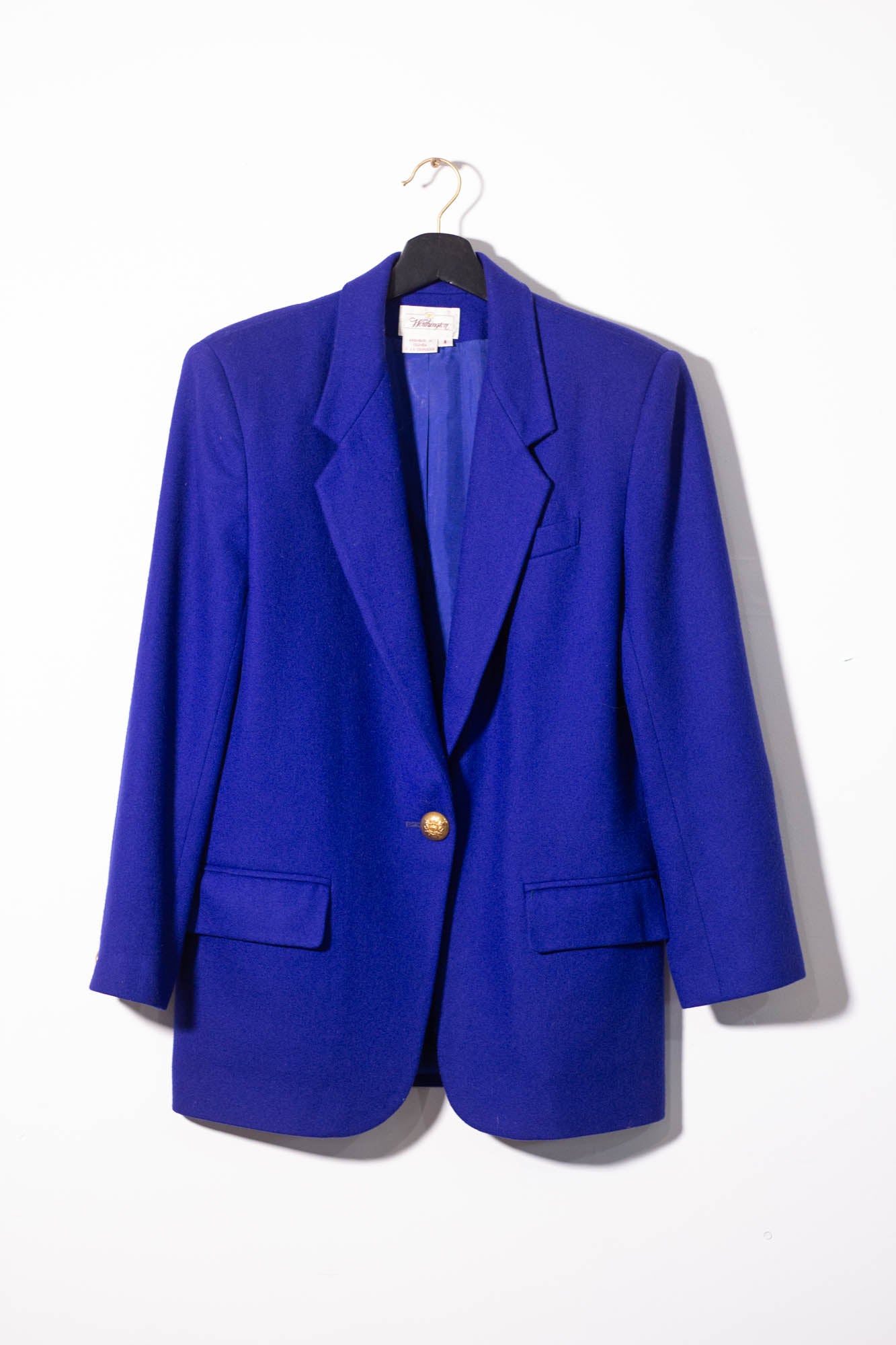 Blue blazer on a hanger against a white background