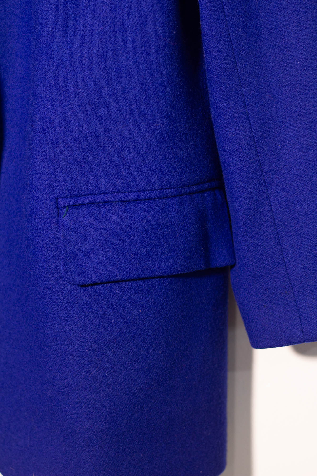 Close-up of a blue suit jacket with a pocket on a white background