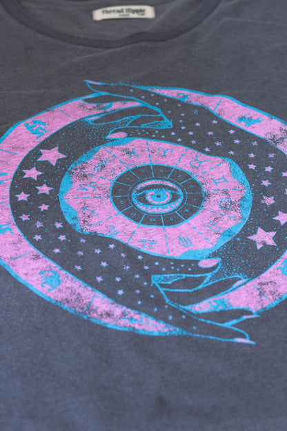 T-shirt with a cosmic design featuring stars and celestial elements on a dark background.